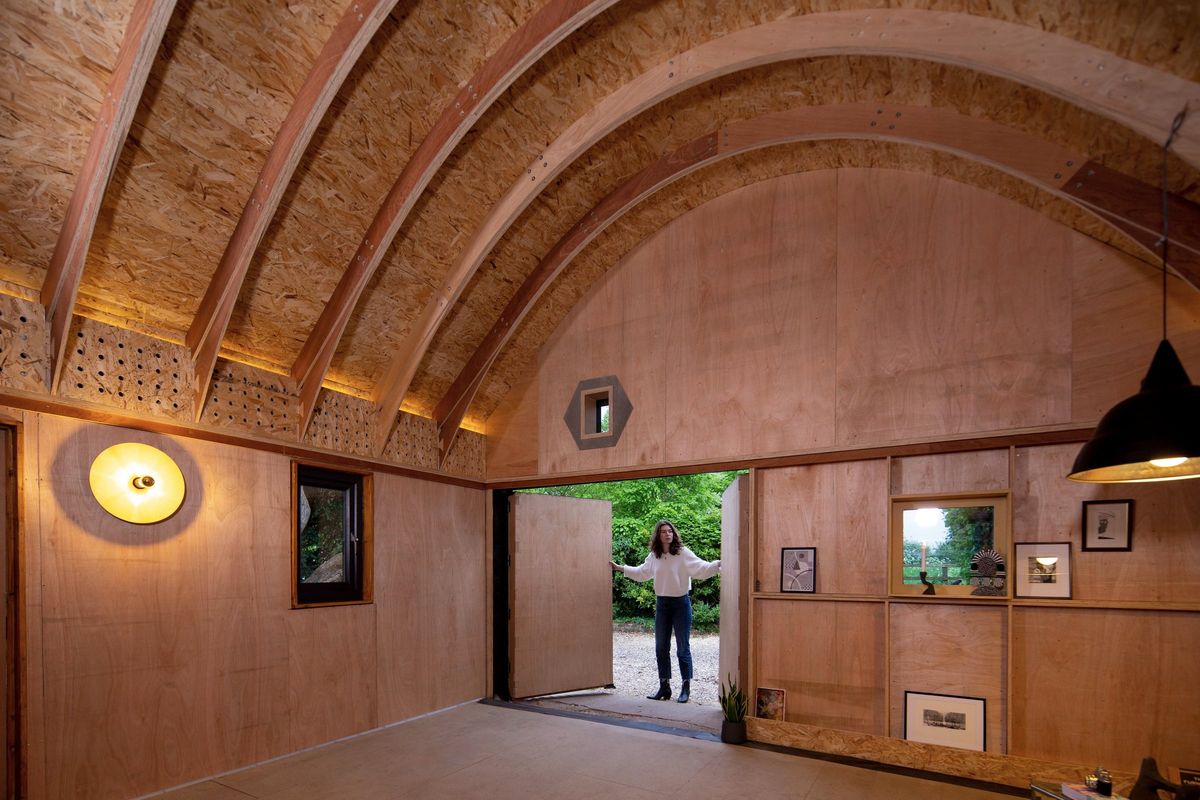 Arched plywood interior of the barn-style studio, door open to the garden