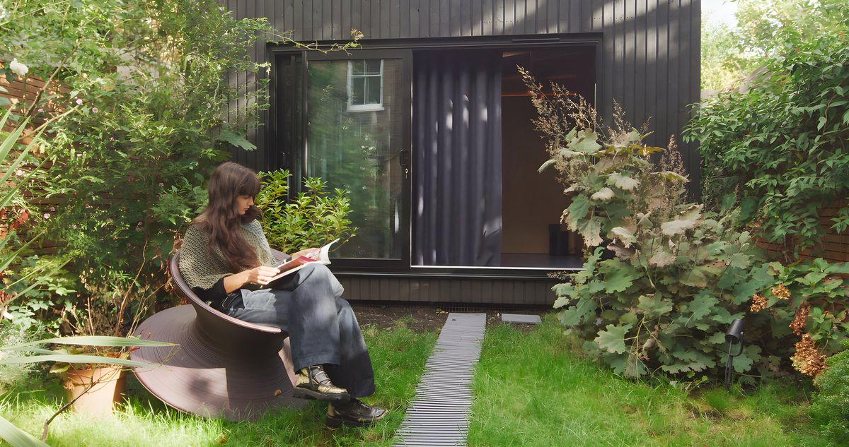 Reading in a chair on the lawn in front of the studio