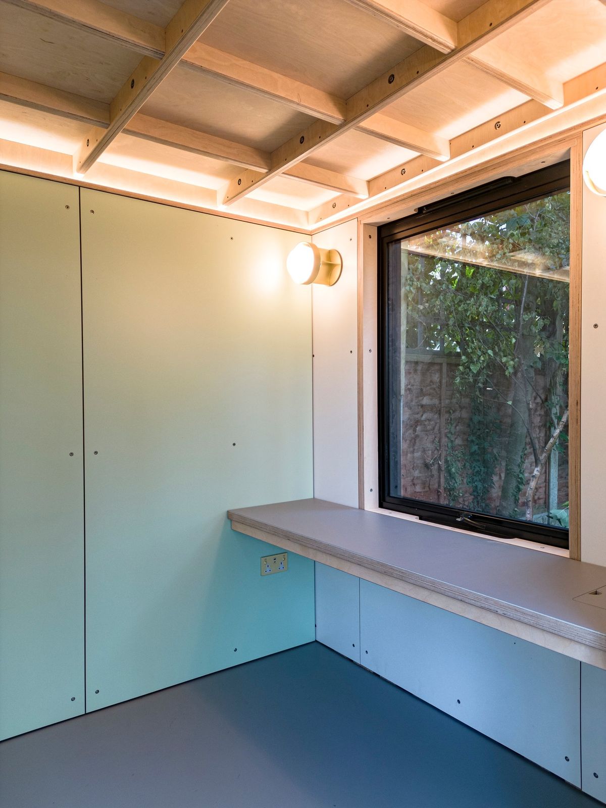 Desk under the window, mint panels and lit ply ceiling