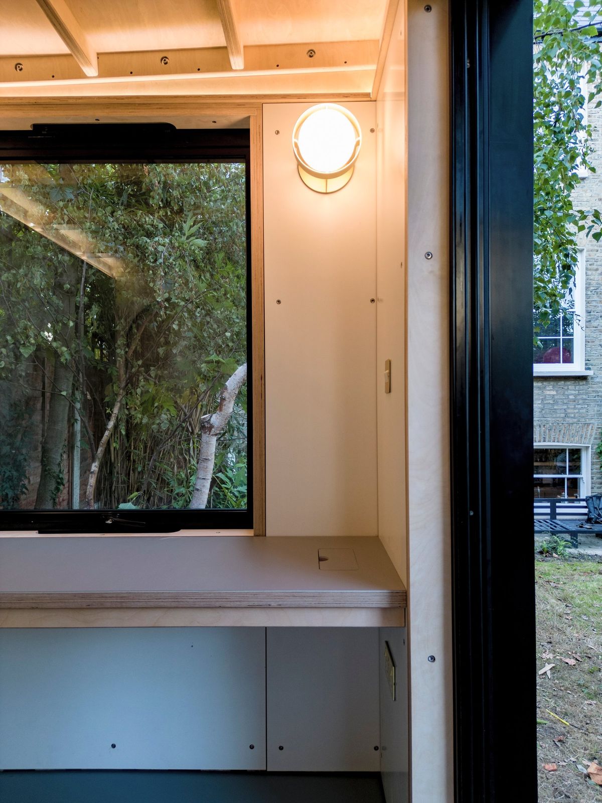 Desk window and brass wall light, garden and house beyond
