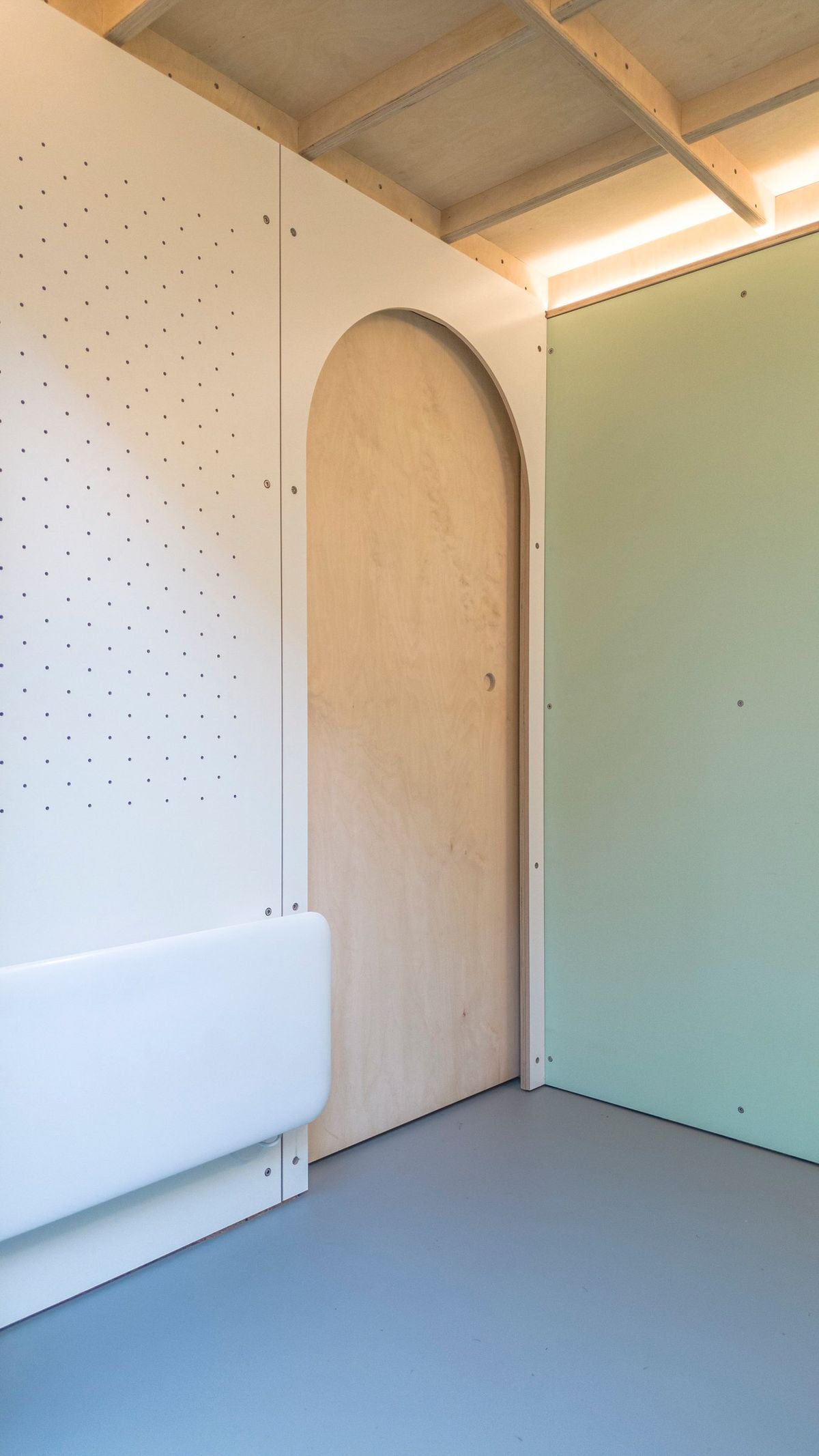 Arched door to the storage room in the peg wall, heater below