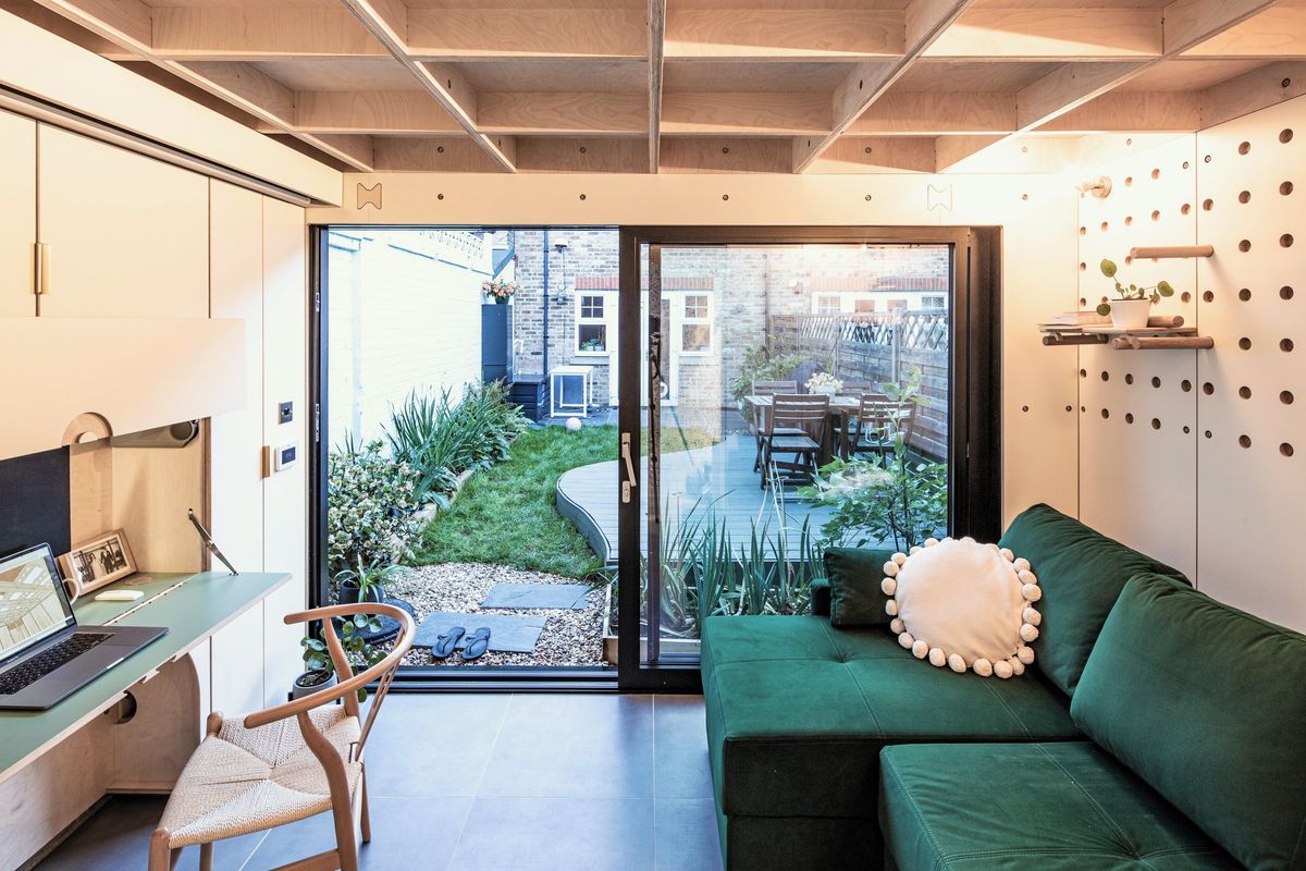 Inside the garden annex: fold-down desk, green sofa and glass doors to the garden