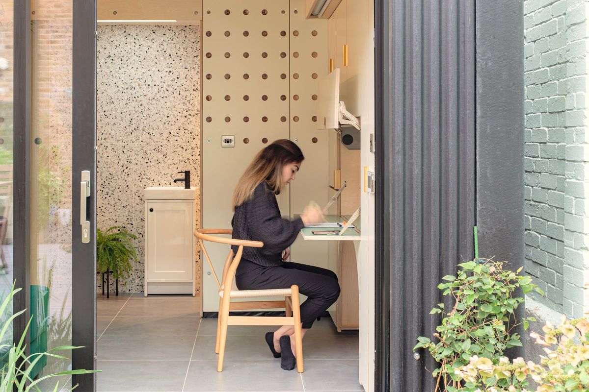 Through the open door: a woman working at the desk, the basin behind