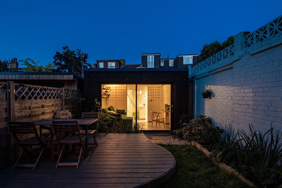The garden annex lit up at dusk at the end of the deck