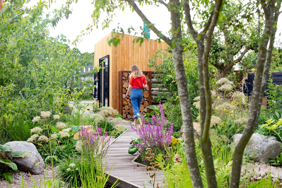 Larch-clad wellness garden room in a lush Richmond garden by Tom Massey, a woman walking up the timber path