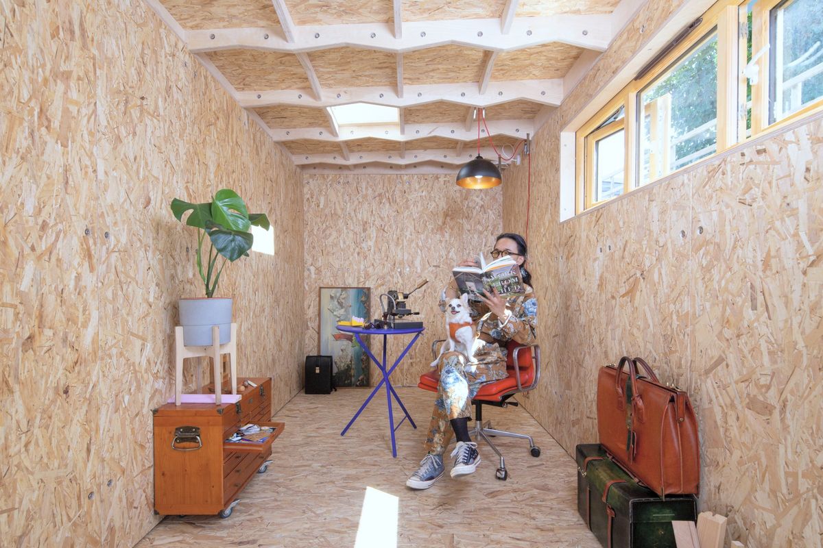 Reading in a red chair at the far end of the OSB-lined studio, skylights above