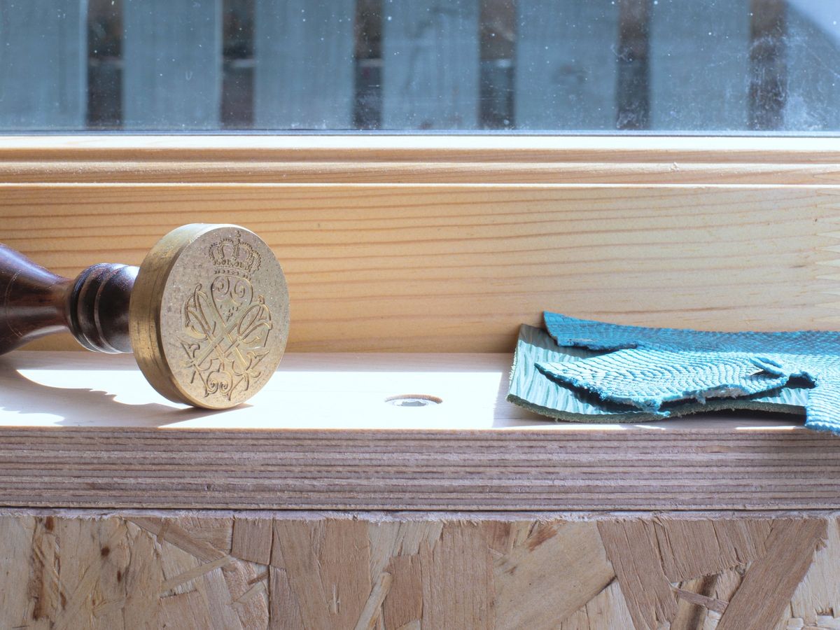 Brass ornament and folded fabric on the plywood window sill, OSB wall below