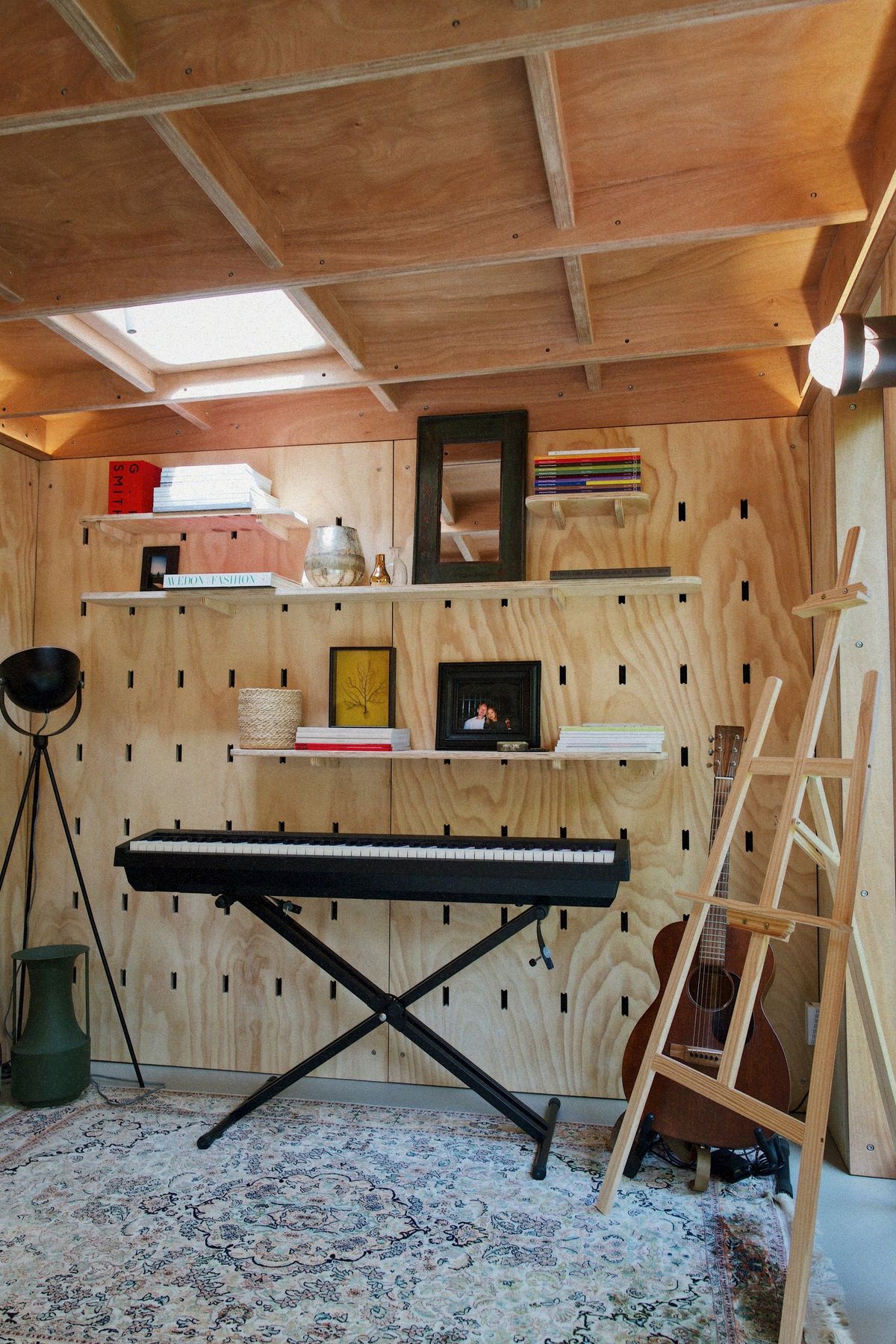 Music corner in the garden studio: keyboard, peg-wall shelves, skylight and rug