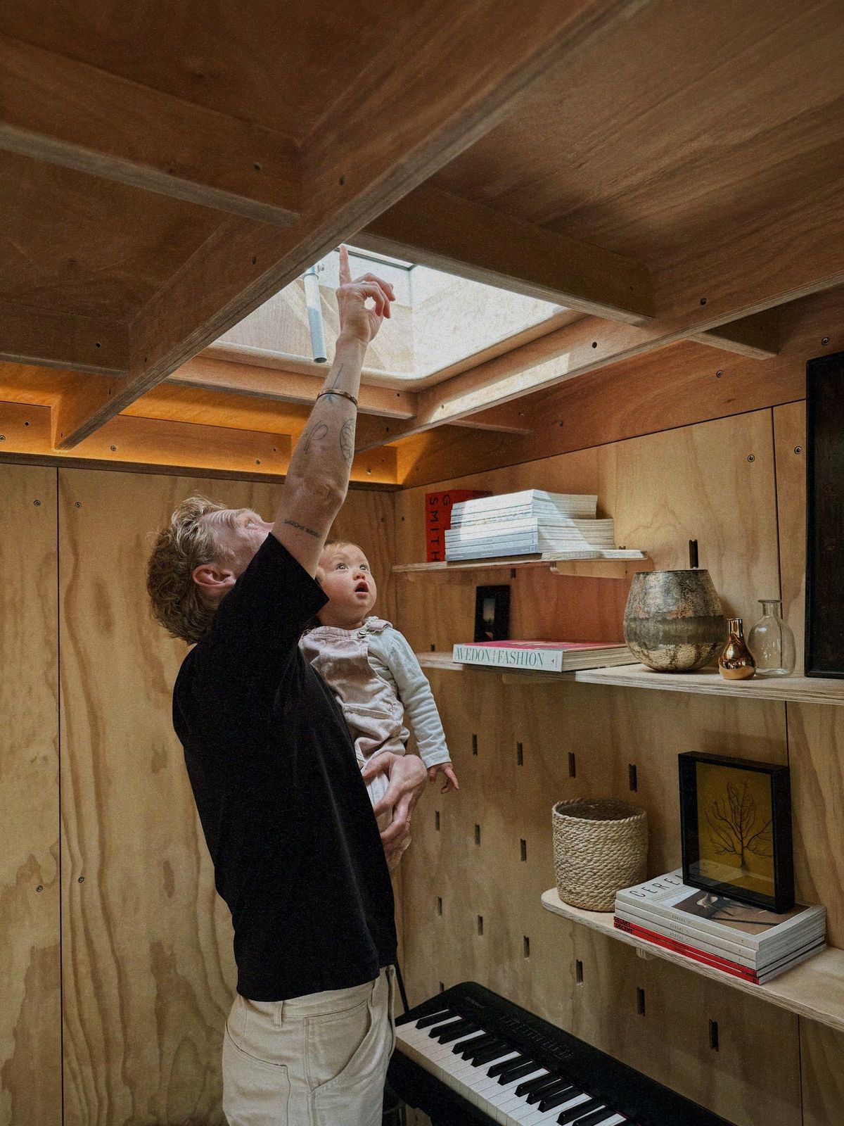 Father lifting a baby towards the skylight, the keyboard below