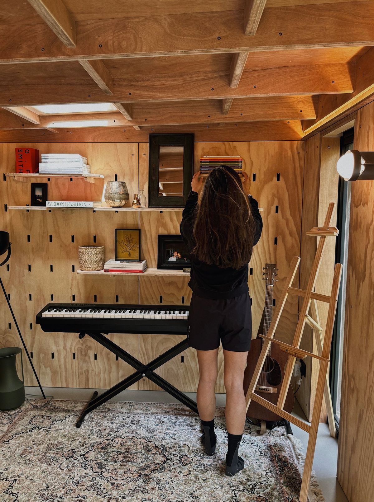 Woman reaching up to the peg-wall shelves above the keyboard