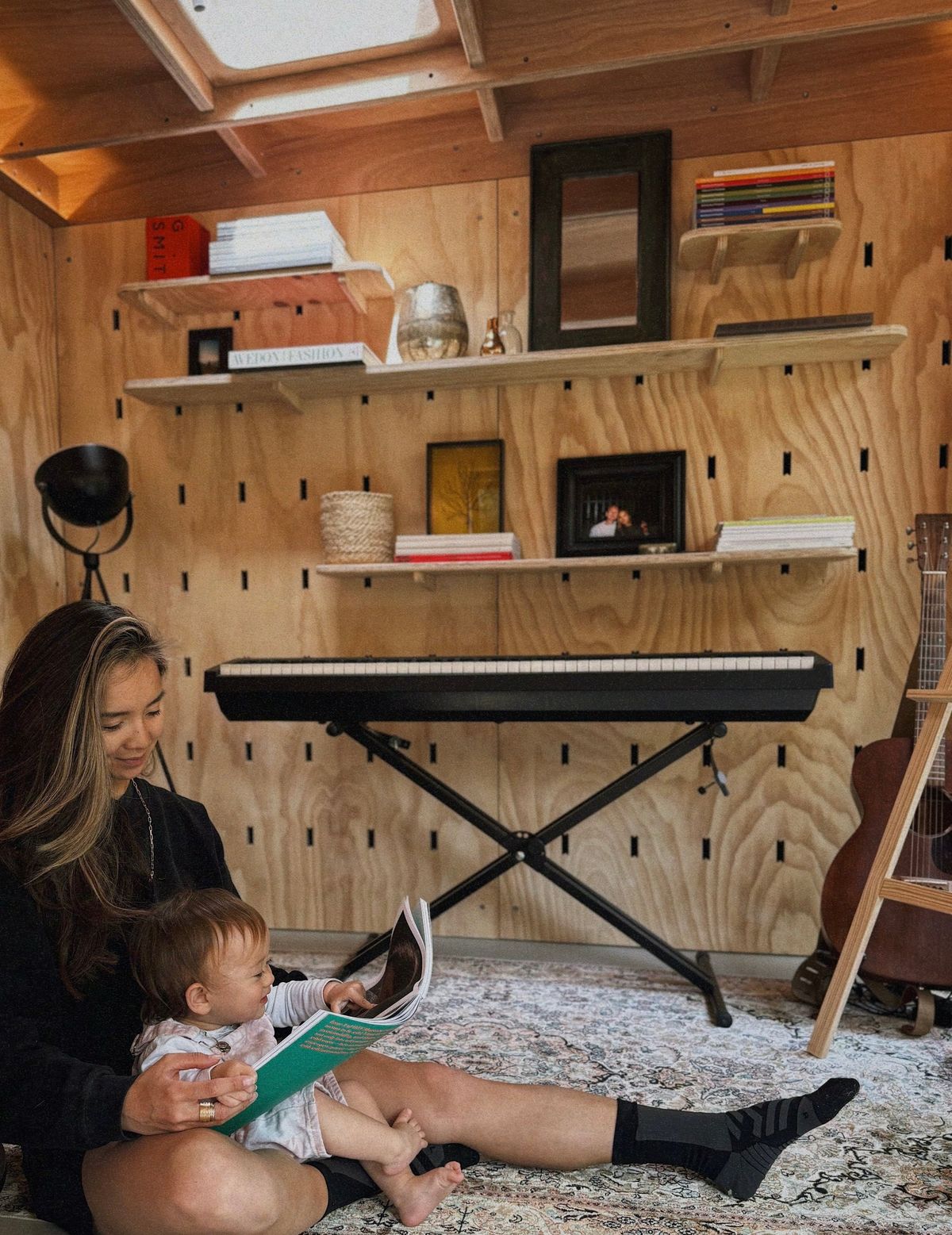 Reading to the baby on the rug by the keyboard