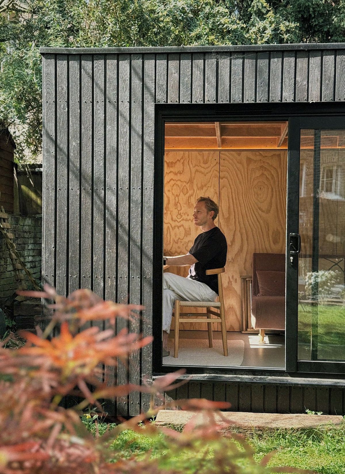 Seen through the open door: working at the desk, maple in front