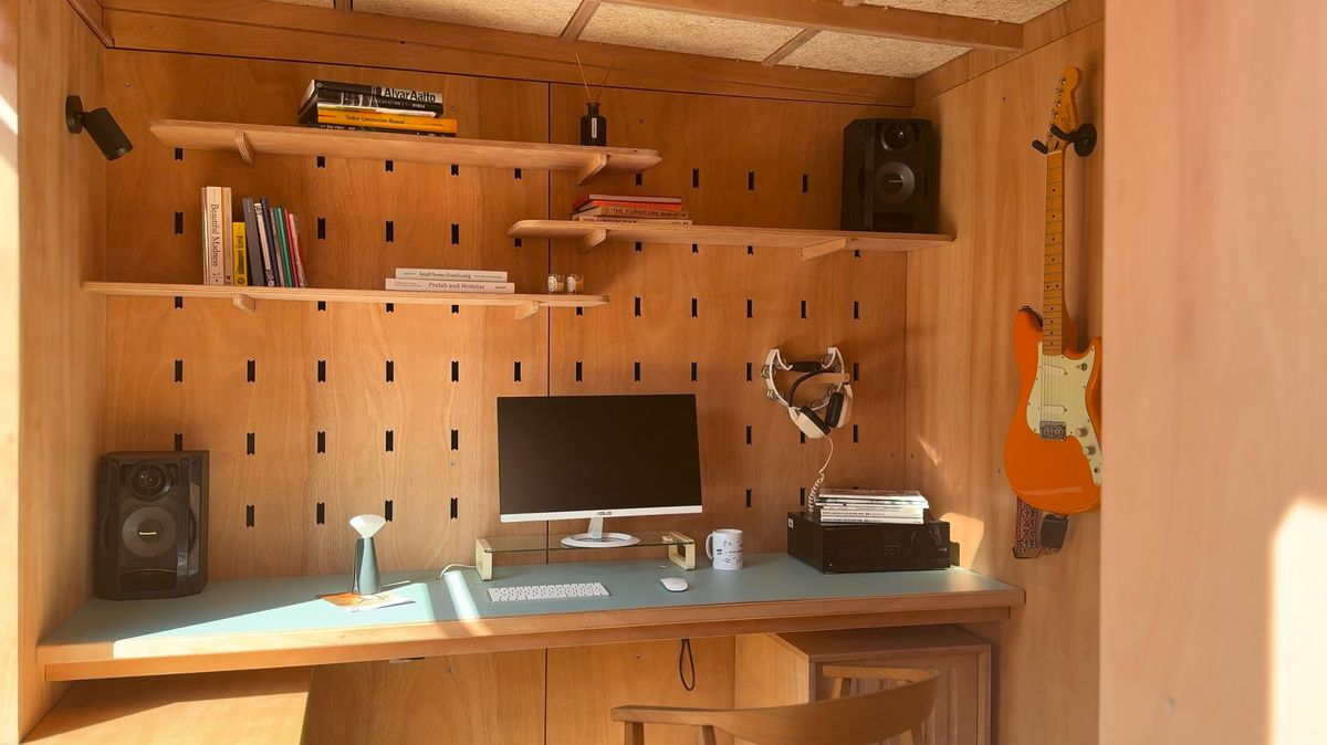 Desk wall: peg board, shelves, speakers, guitar and monitor