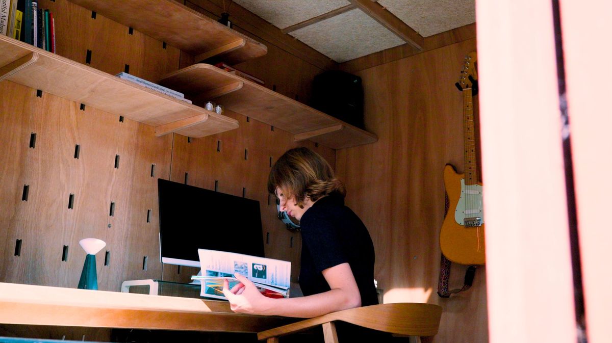 Reading at the desk under the peg-wall shelves
