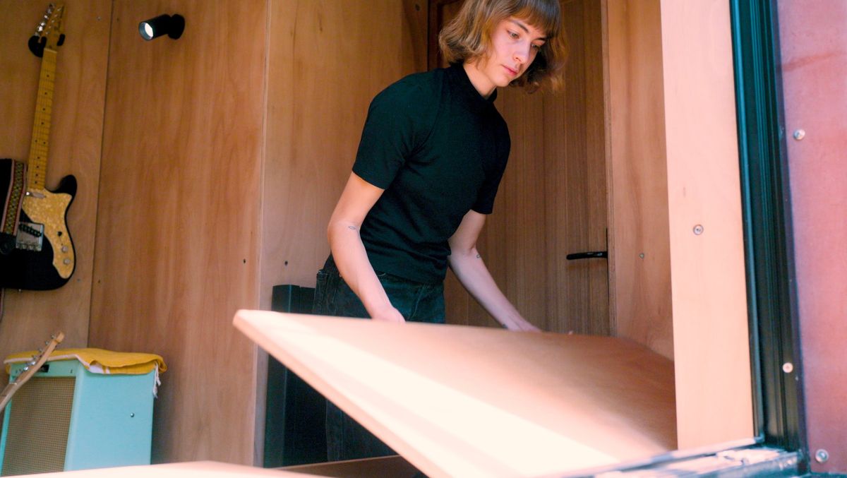 Lifting the hinged lid of the plywood storage bench
