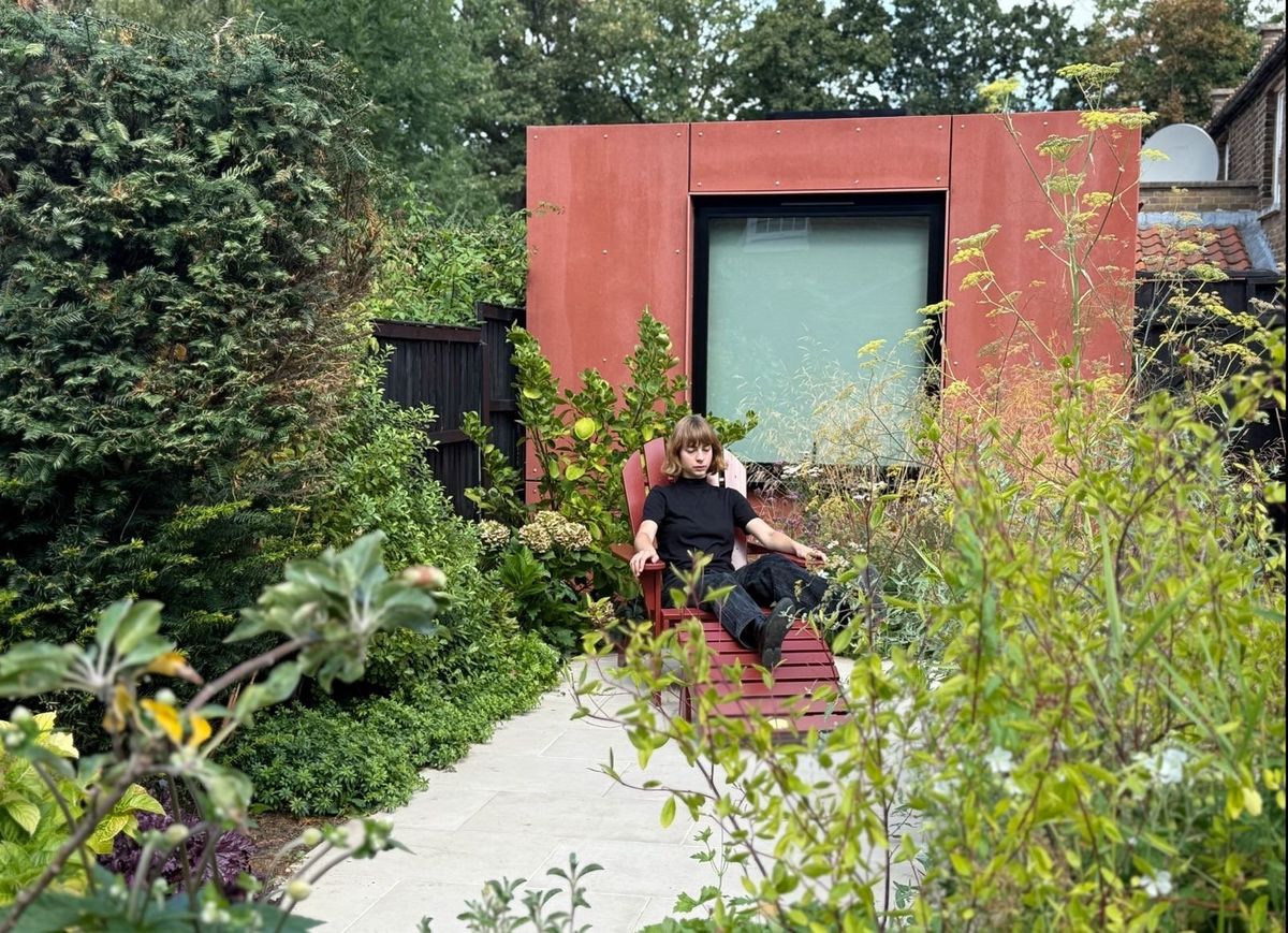 Relaxing on a red lounger in the garden, the pink music studio behind