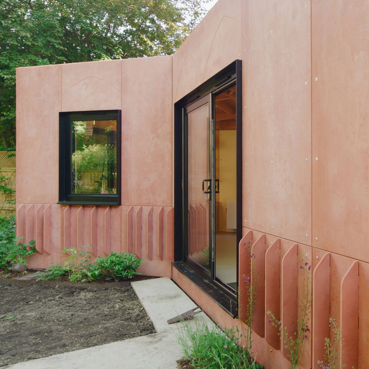 Corner of the V-shaped studio: red Viroc cladding, a window and fins at the base