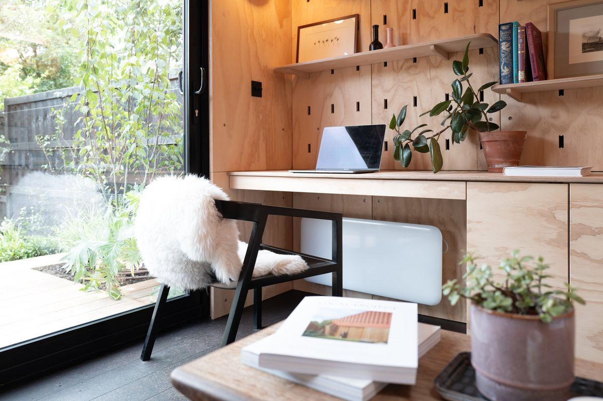 Home office desk and sheepskin chair by the glazed door, with pegboard shelves above
