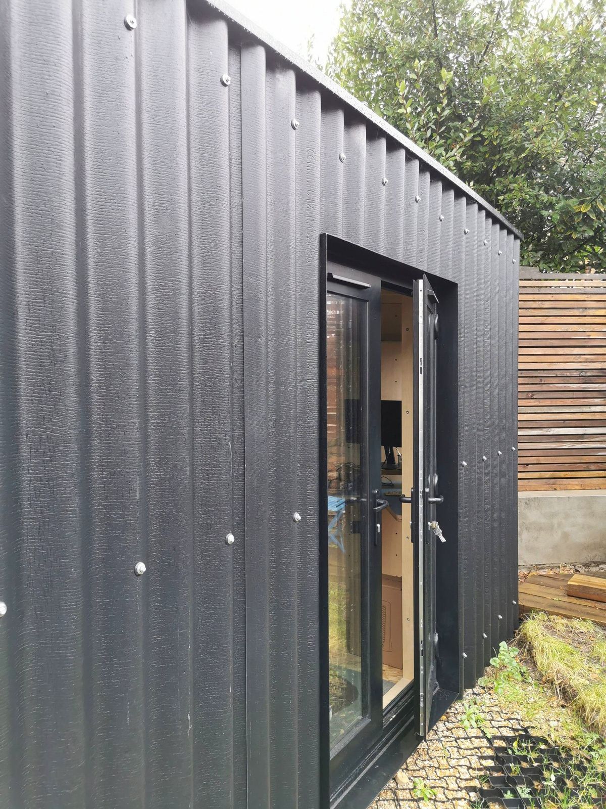 Black corrugated cladding and the glazed door of the corner studio