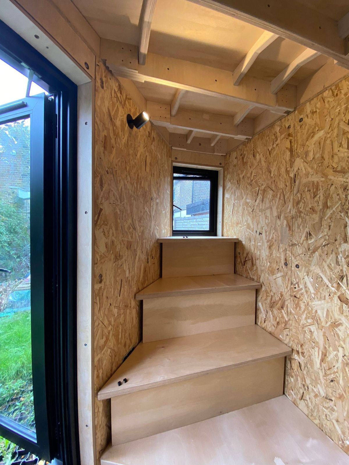 Ply steps rising into the narrow point of the triangular room, slot window above