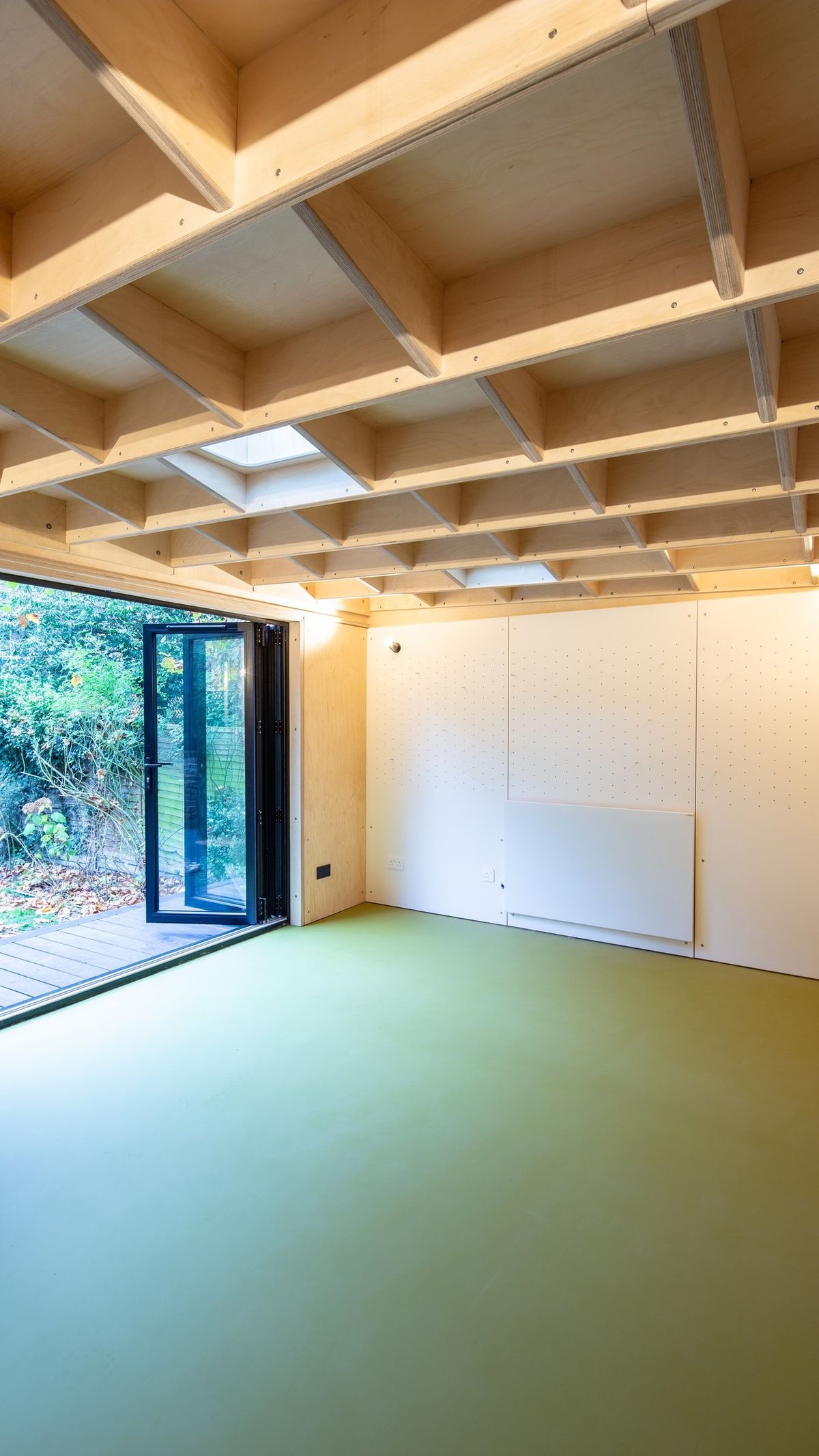 Full height of the room: green floor, ceiling joists, doors