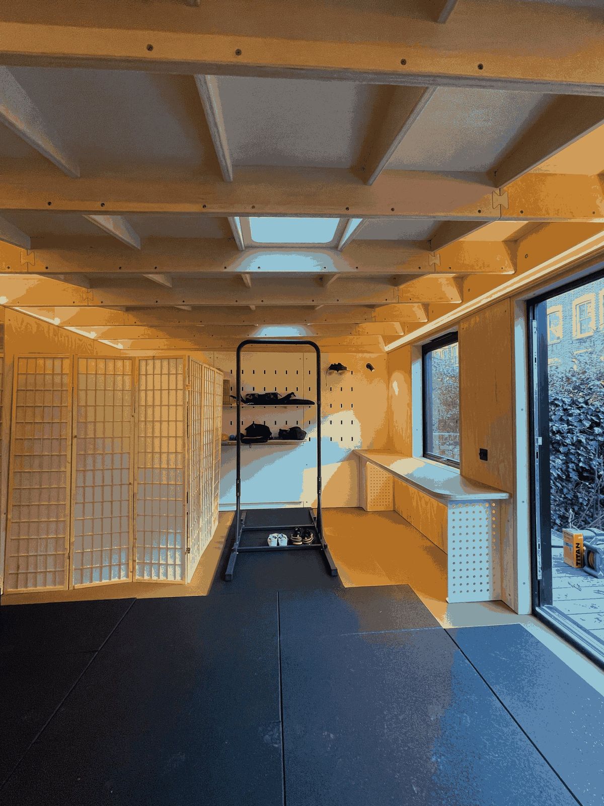 The garden gym: rubber floor, skylight in the ply ceiling grid, screens and a rack