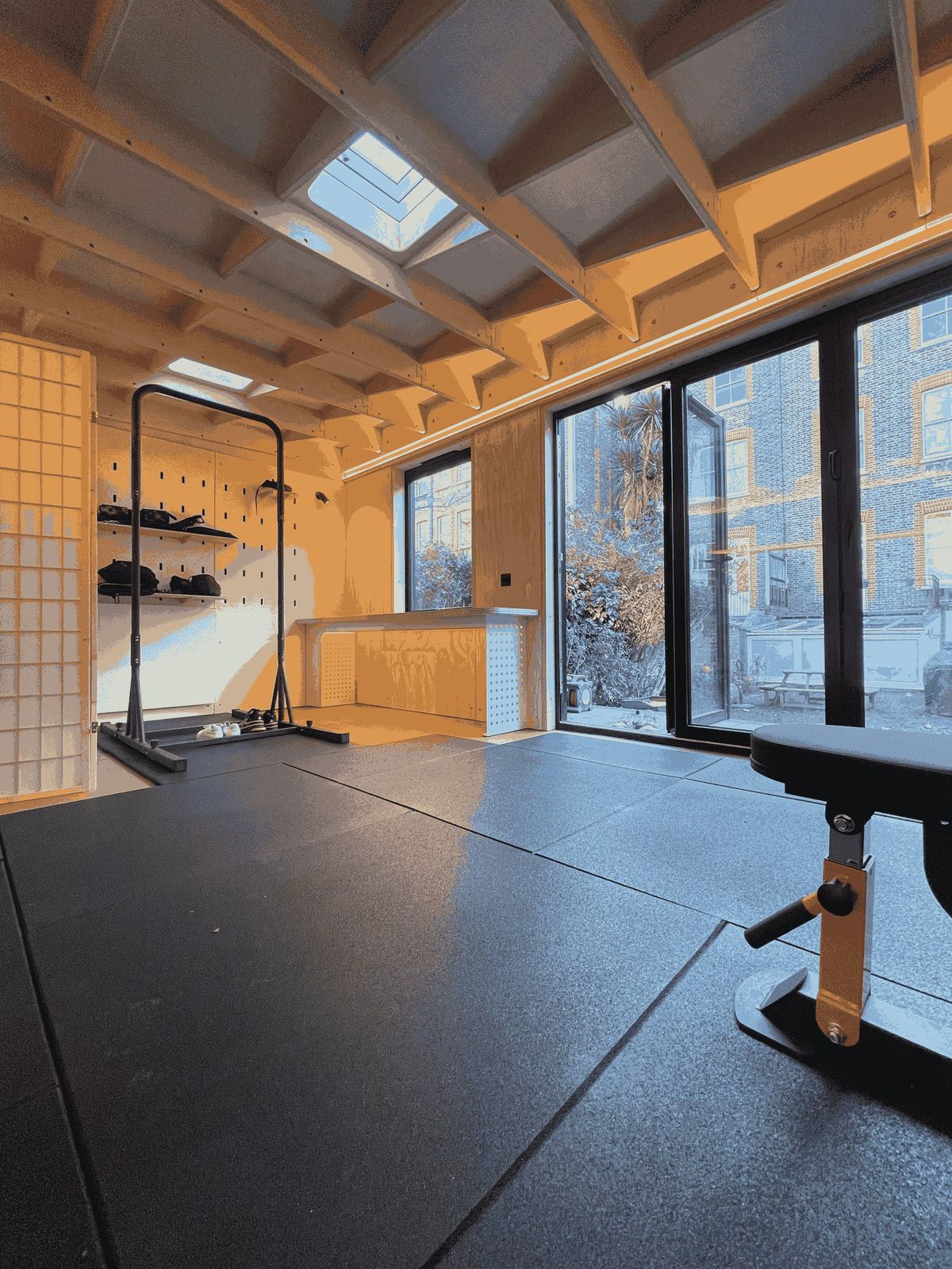 Gym room with a weights bench, rubber floor and full-height glazing to the garden
