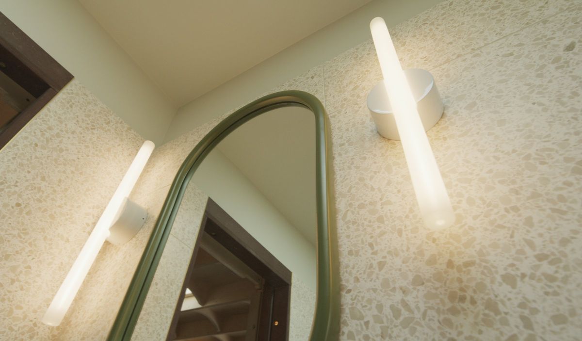 Green arched mirror and tube lights on terrazzo