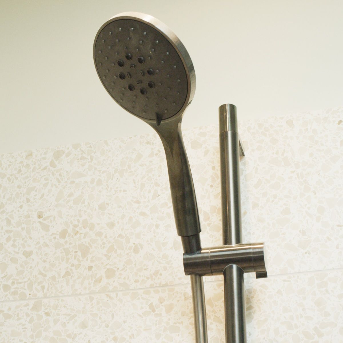 Shower head and rail against the terrazzo tiles of the en suite